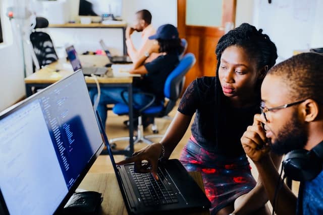 Female PM working at with person at computer