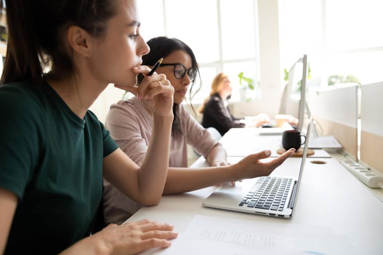 Two women working together on a project using their computer