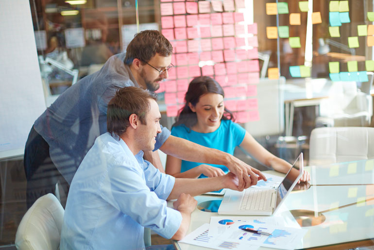 Three colleagues at computer discussing agile framework options