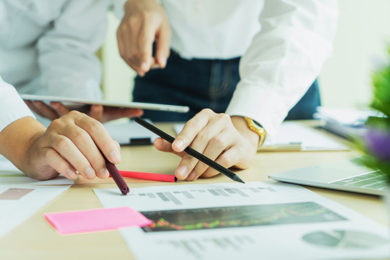 Two Business colleagues standing around table discussing
