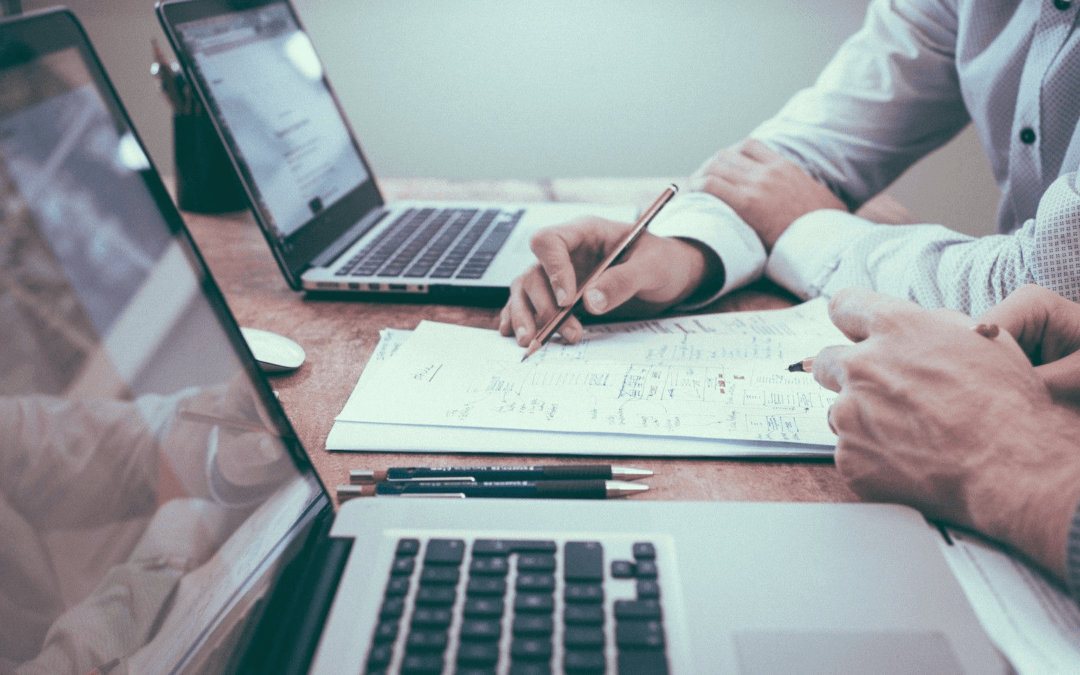 Close up of two individual's hands at computers on project management