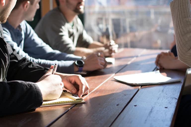 Group of co-workers at a table listening to a trainer